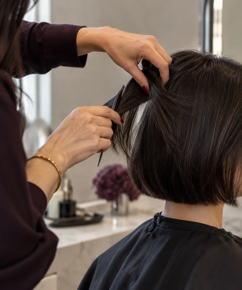 A stylist carefully sectioning a client's dark bob haircut